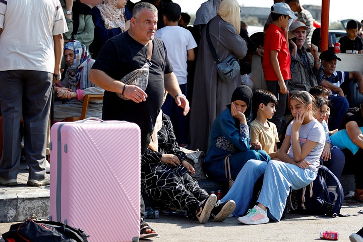 10月14日,拥有双重国籍的巴勒斯坦人在加沙南部拉法市(Rafah)与埃及的过境通道等待获准进入埃及避难。(路透社)