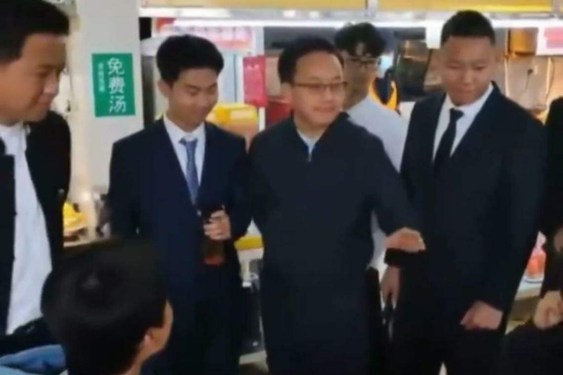 学生模仿领导的样子与就餐学生进行交谈。(视频截图)