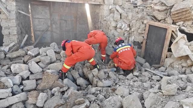 地震灾区有很多房屋被毁、建筑物倒塌。救援人员在废墟中搜寻生还者,并为当地居民分发厚毛毯。