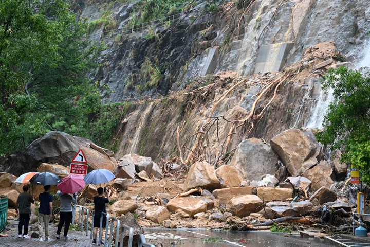 持续暴雨造成港岛东区筲箕湾耀兴道一个地段发生滑坡泥石流,滑落的巨石阻断道路。(法新社)