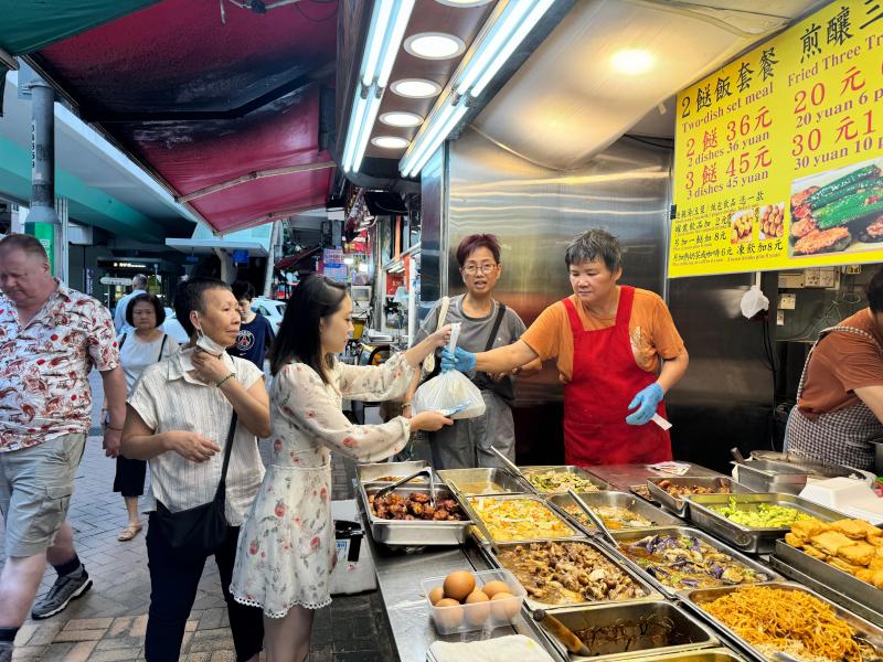 两餸饭提供的菜式多元化,一般只需三四十港元,买起来也方便快捷,对冯华颖(中)这种平日中午只有一小时吃饭的人来说,经济实惠又省时。(戴庆成摄)